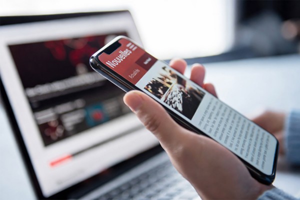 cell phone in hand in front of laptop